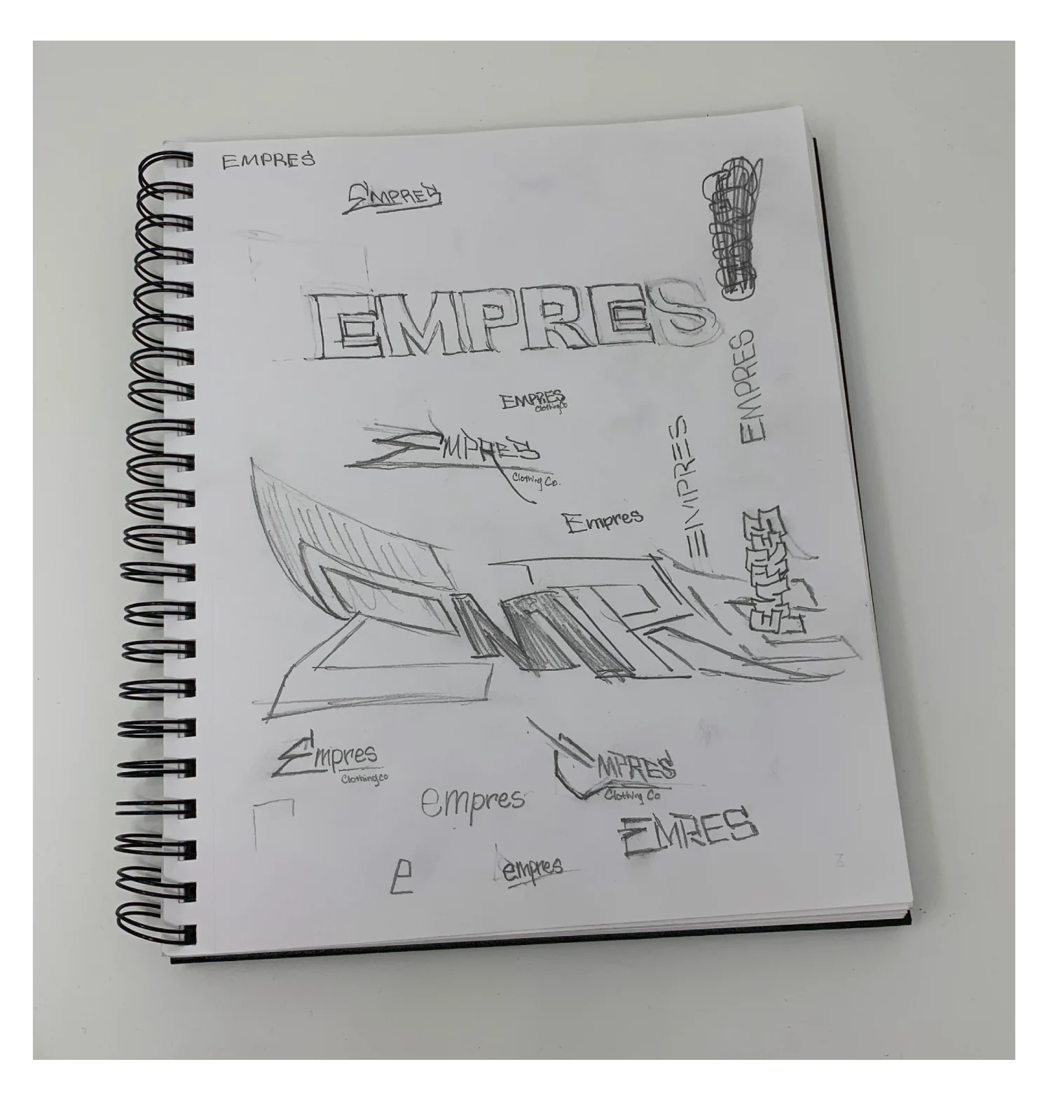 Sketchbook page full of pencil Empres logo explorations: block letters, 3D extruded type, script tags and early versions of the E mark